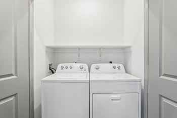 Two white front loading washing machines in a laundry room.